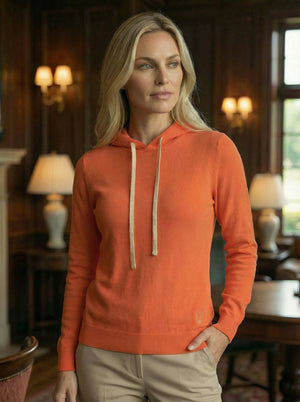 Hoodie Dogleg Clubhouse femme corail porté par une golfeuse — hoodie cachemire, golf Suisse